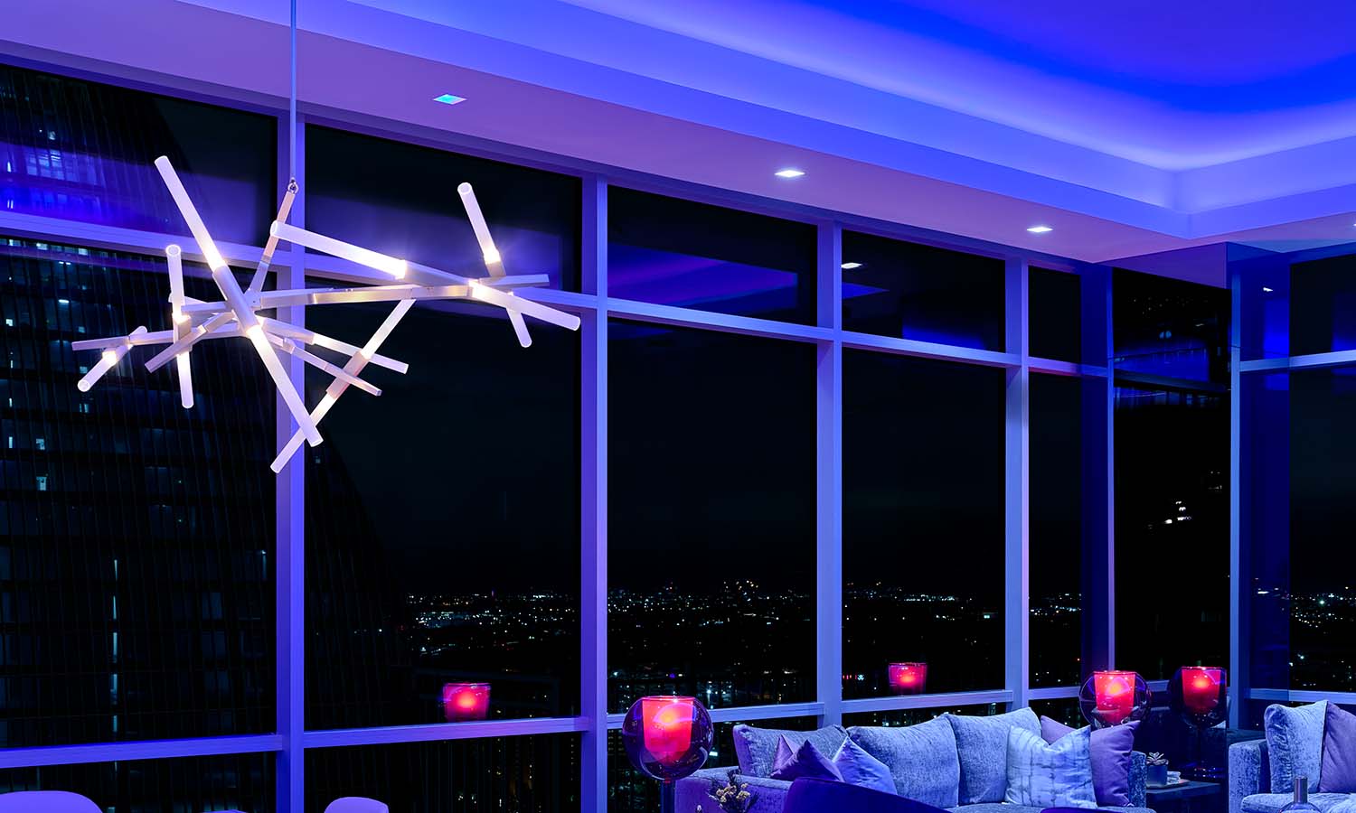 High-rise living room washed in deep blue from Ketra smart downlights.