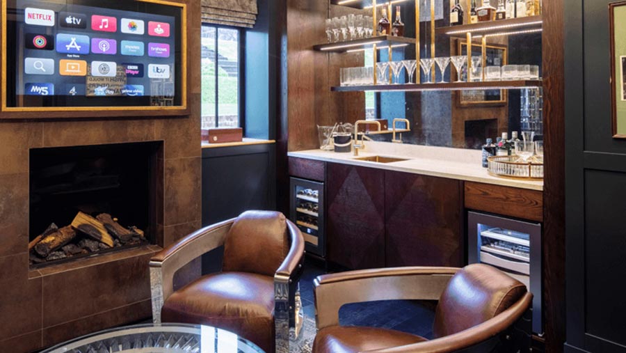 Luxury home bar area with two leather armchairs, a fireplace, and a television