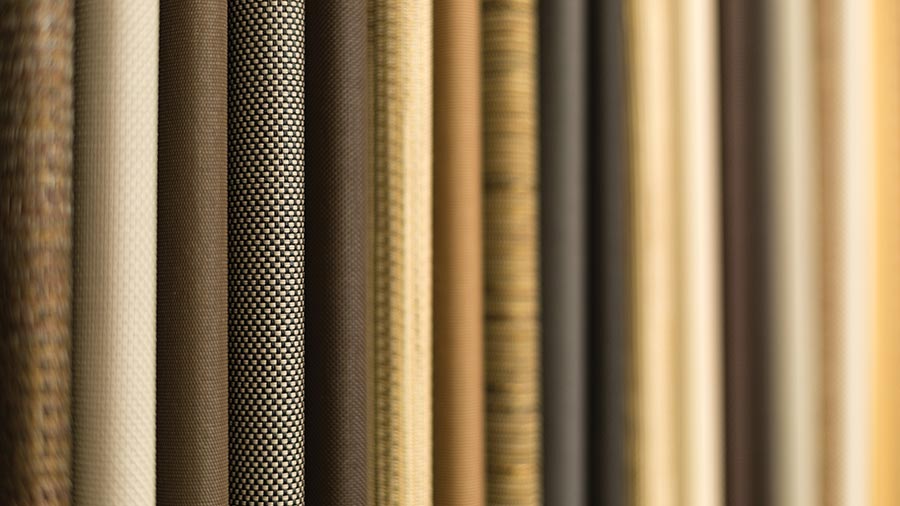 A variety of textured fabric rolls in neutral shades of beige and brown