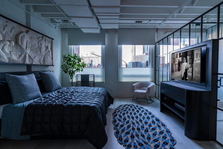 Modern bedroom with exposed ceiling ducts, dark bedding, and a media console