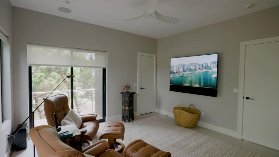 Modern sitting room with brown leather recliners, a large television, and a sliding glass door