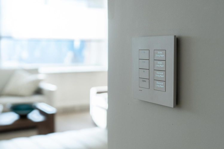 Close-up of a wall-mounted smart home lighting and shade control keypad in a living area
