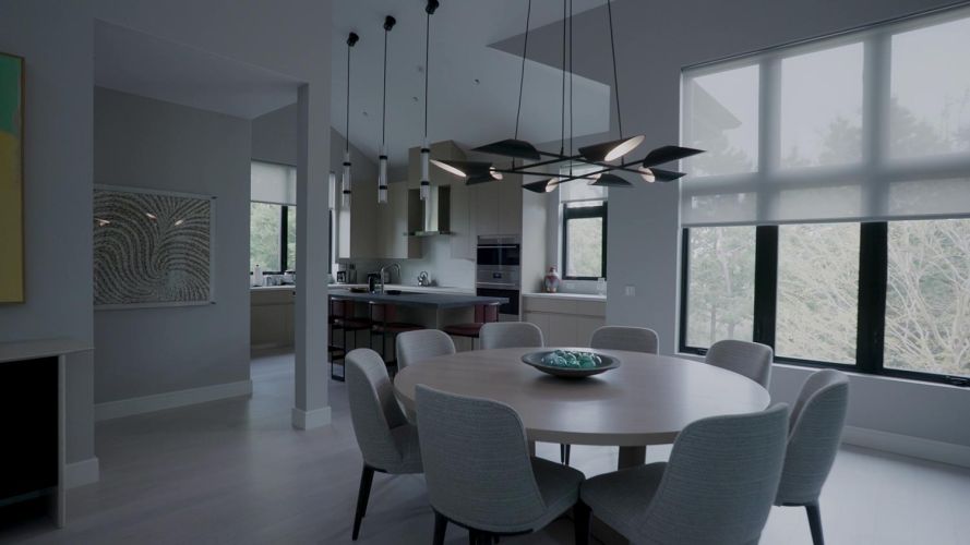 Open-concept dining space and kitchen with a round table, grey chairs, and modern chandeliers