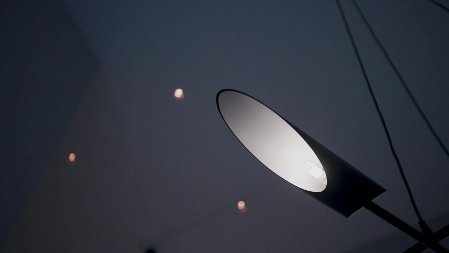 Close-up of a modern black angled light fixture illuminated against a dark ceiling