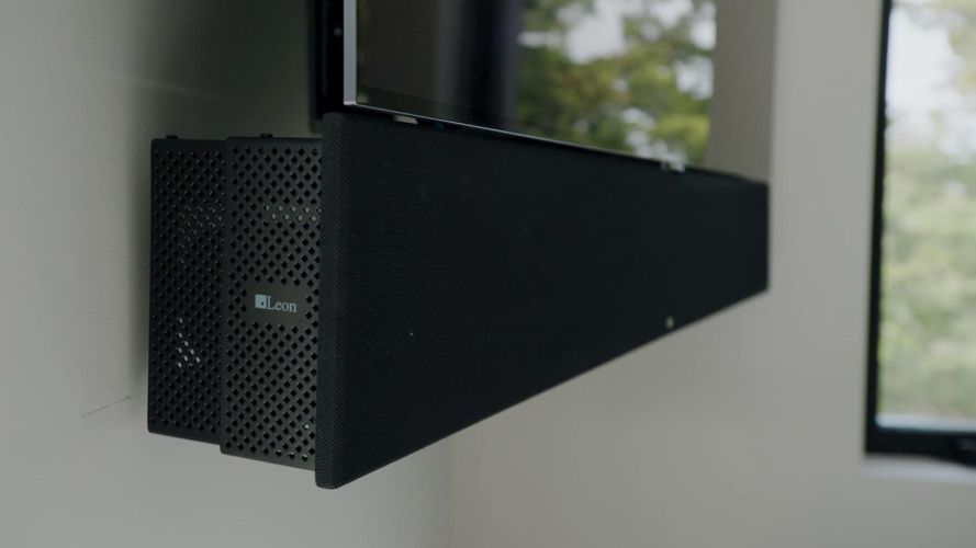 Black custom speaker bar mounted below a wall-mounted flat-screen television
