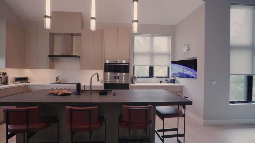 Contemporary kitchen featuring a dark island with red barstools, stainless appliances, and a TV