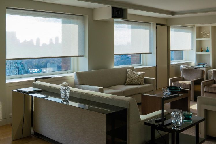 Spacious living room setup with multiple neutral-toned couches, tables, and city views