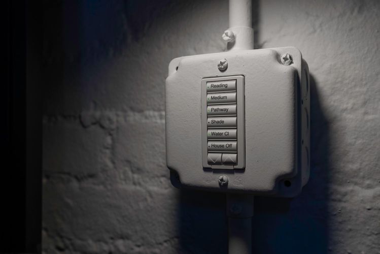 Industrial wall-mounted light switch keypad with glowing green indicator lights