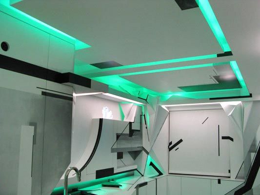 Abstract modern kitchen with sharp geometric angles, graphic black lines, and green cove lighting