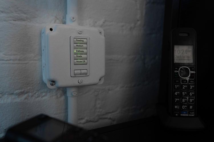 White industrial keypad on a brick wall next to a cordless phone