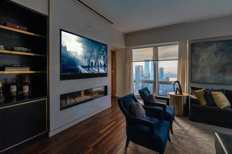 Angle view of a contemporary living area with wood floors, blue armchairs, and fireplace