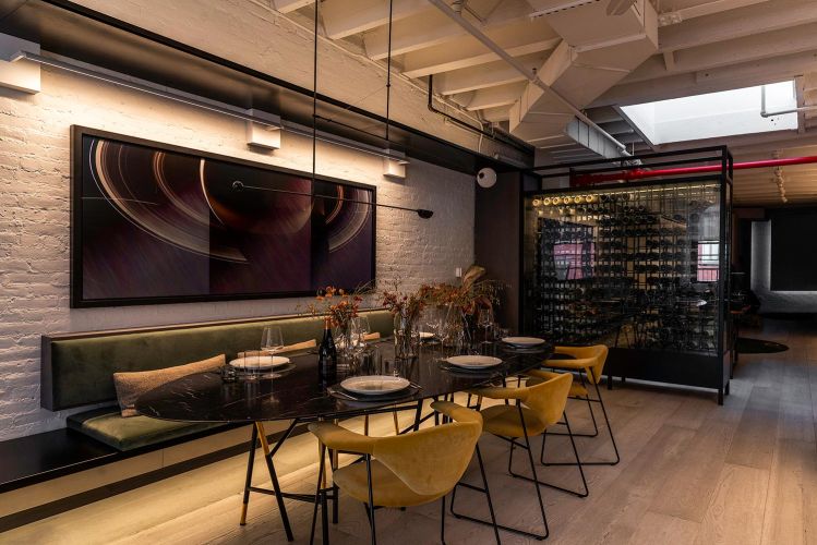 Long oval dining table set for a meal in a modern room with a wine cellar