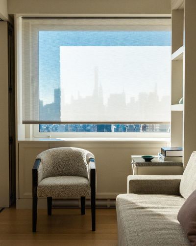 Framed view of an armchair by a window overlooking a faint city skyline silhouette