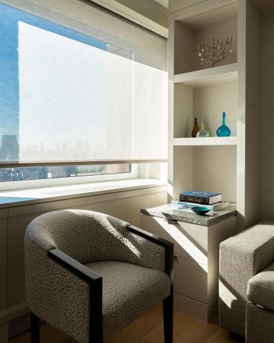 Close-up of a patterned accent chair, marble-top side table, and built-in display shelves