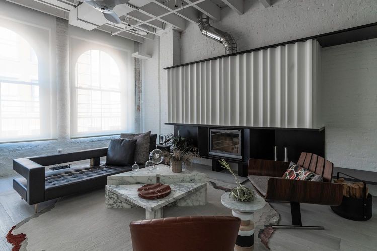 Modern living room with a marble coffee table, black sofa, and white fireplace cover